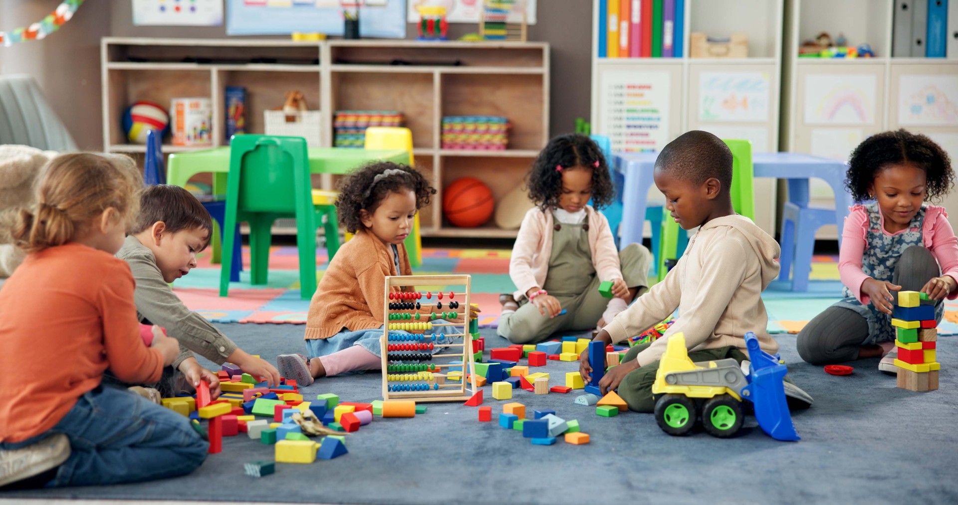 Kids, students and play with blocks in classroom for learning, problem solving and creative activity. Children, toys and floor for education game, puzzle solution and motor growth in kindergarden